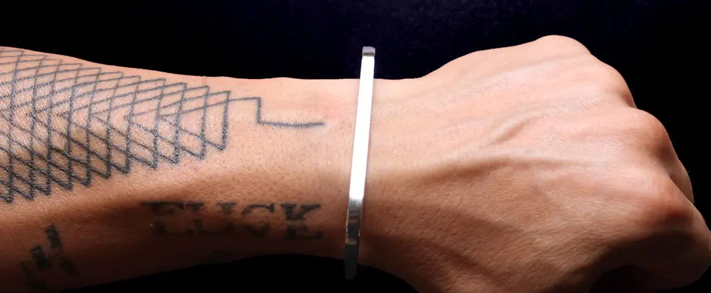 brazo de hombre tatuado con pulsera de plata